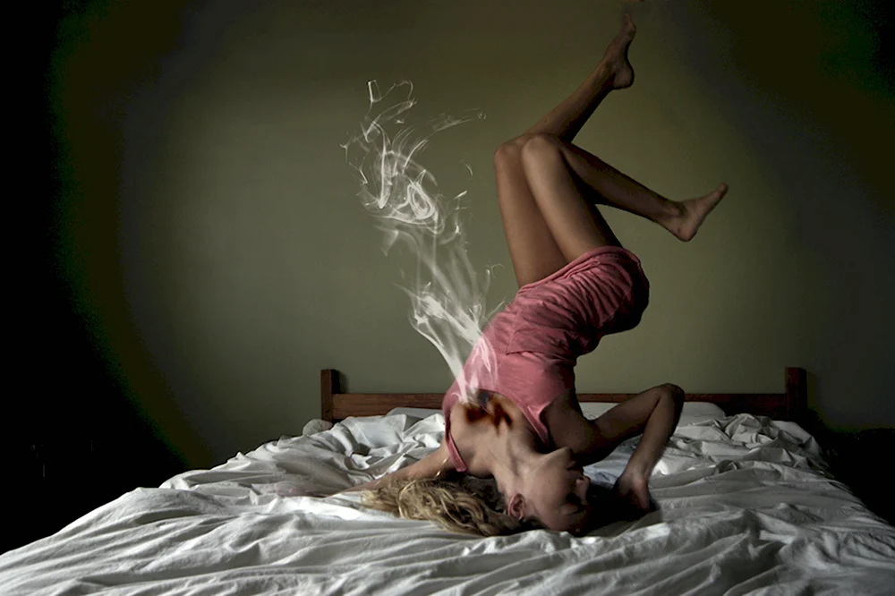 Девушка с сигаретой на кровати