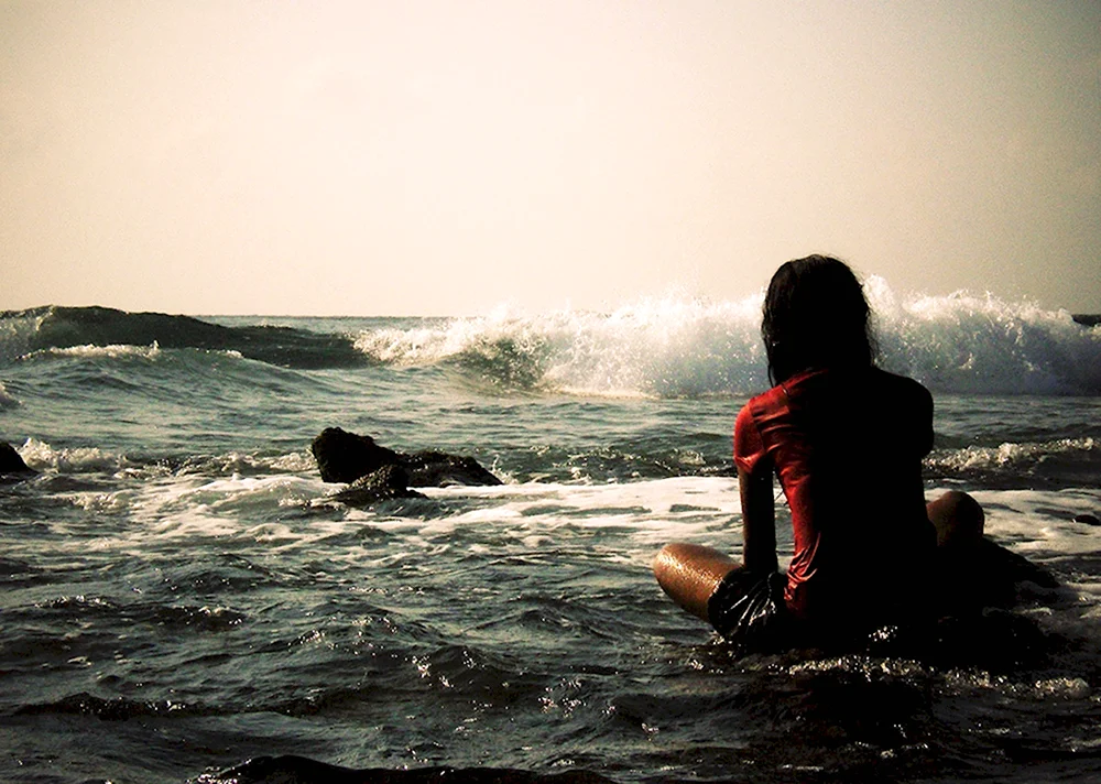 Девушка сидит возле моря