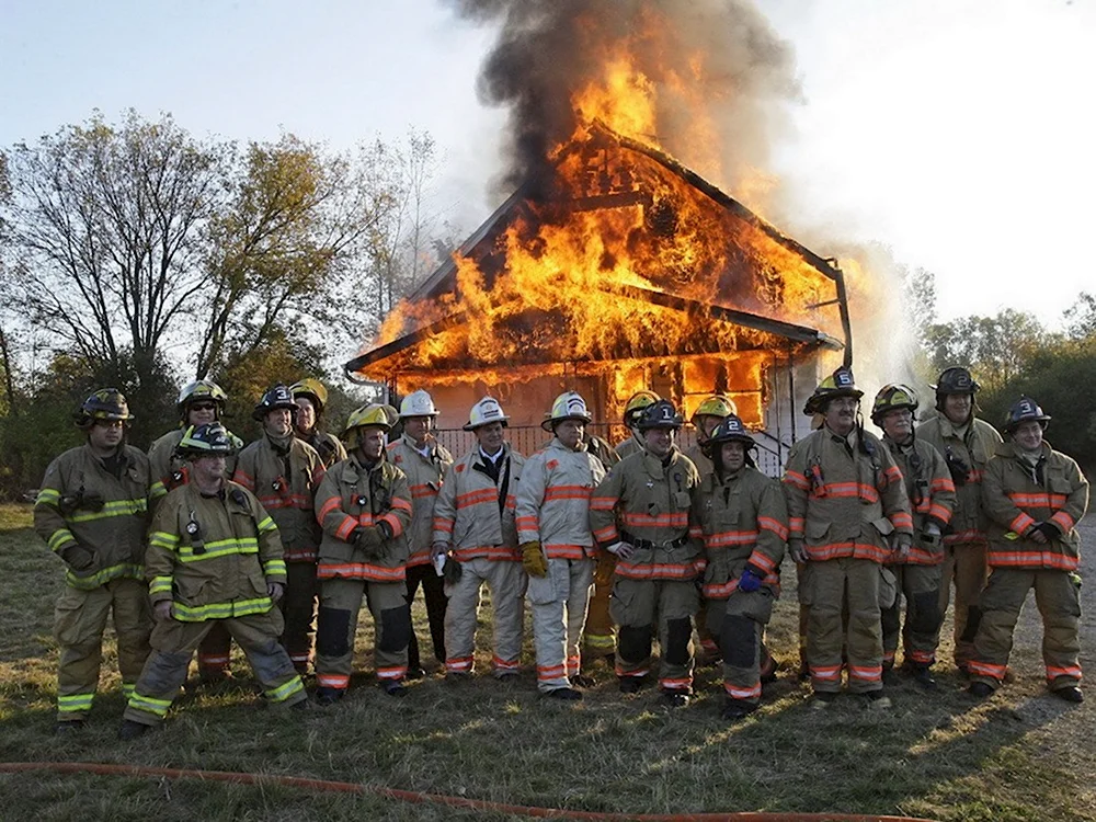 Пожарные на фоне горящего дома
